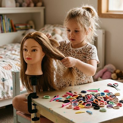 Enfant créant une coiffure sur tête à coiffer